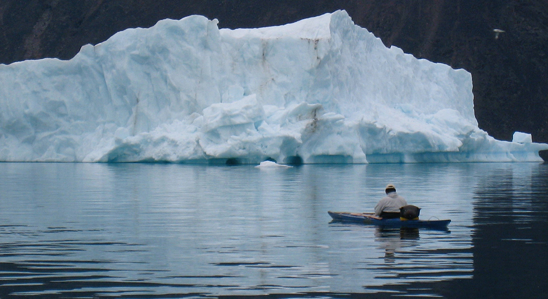 Man in kayak with iceberg in the distance. Photo: The NOW project